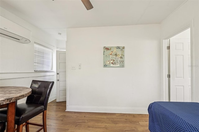 bedroom with an AC wall unit, baseboards, and wood finished floors