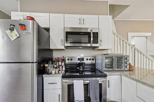 kitchen featuring white cabinetry, crown molding, a toaster, and appliances with stainless steel finishes