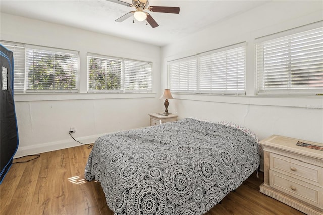 bedroom with a ceiling fan, baseboards, and wood finished floors