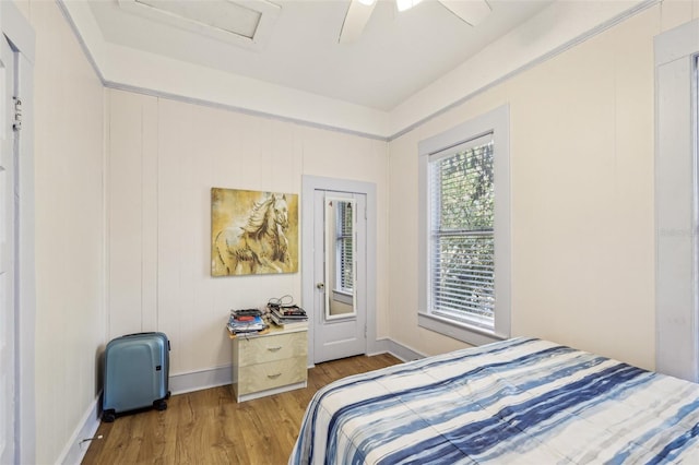 bedroom with ceiling fan, baseboards, attic access, and wood finished floors