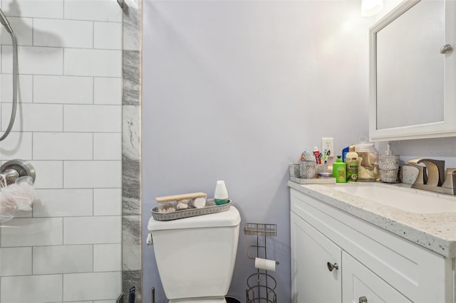 bathroom with vanity, toilet, and tiled shower