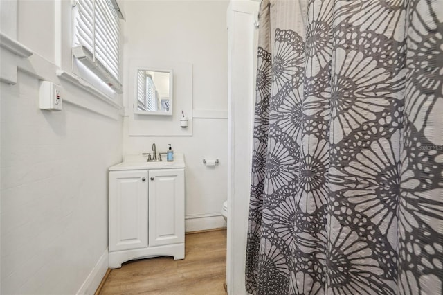 bathroom with toilet, vanity, walk in shower, and wood finished floors