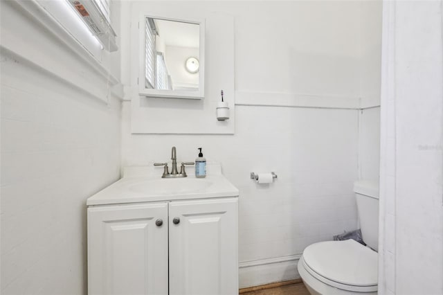 half bathroom with tile walls, toilet, and vanity