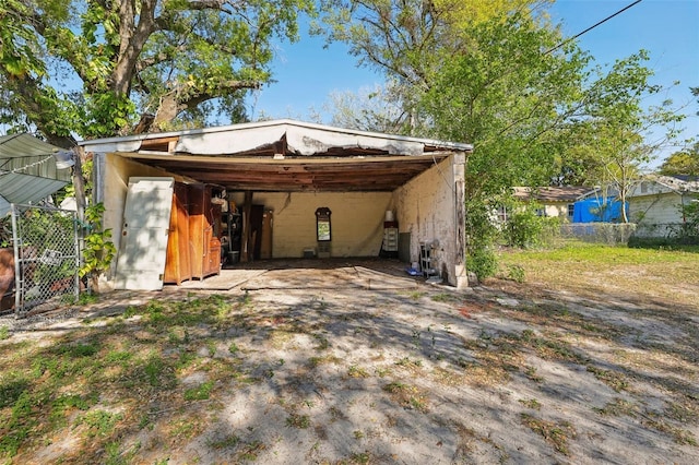 rear view of house with an attached carport, an outdoor structure, driveway, and fence