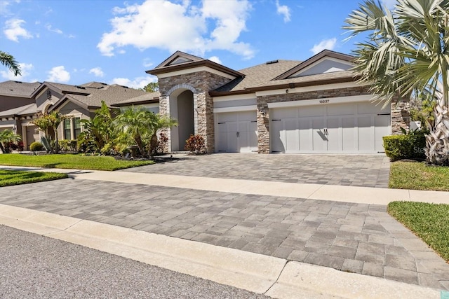 view of front of house featuring stone siding, stucco siding, an attached garage, and decorative driveway