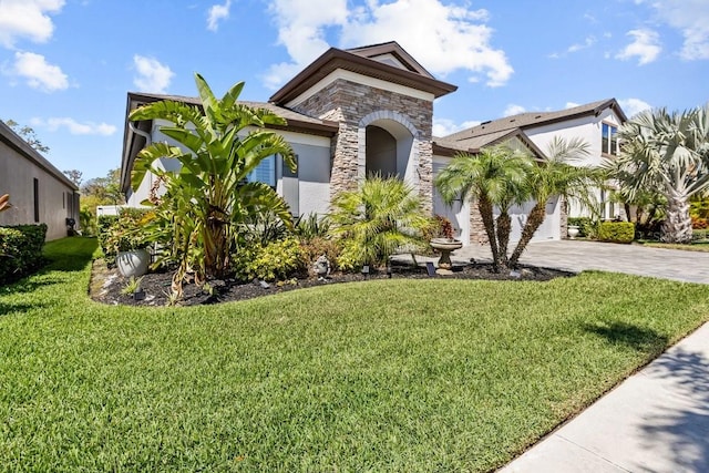 view of front of house featuring stucco siding, stone siding, and a front lawn