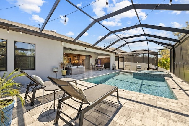 view of swimming pool featuring a pool with connected hot tub, ceiling fan, glass enclosure, an outdoor hangout area, and a patio area