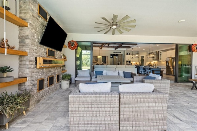 living area with an outdoor stone fireplace and ceiling fan