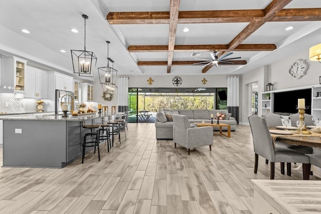 interior space with beam ceiling, ceiling fan with notable chandelier, and coffered ceiling