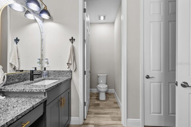 bathroom with visible vents, toilet, wood finished floors, baseboards, and vanity