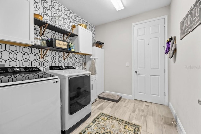 clothes washing area with cabinet space, washer and dryer, light wood-style flooring, and baseboards