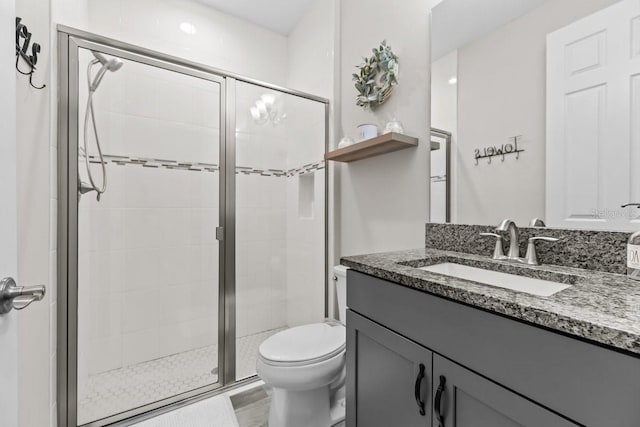 bathroom with a shower stall, toilet, and vanity