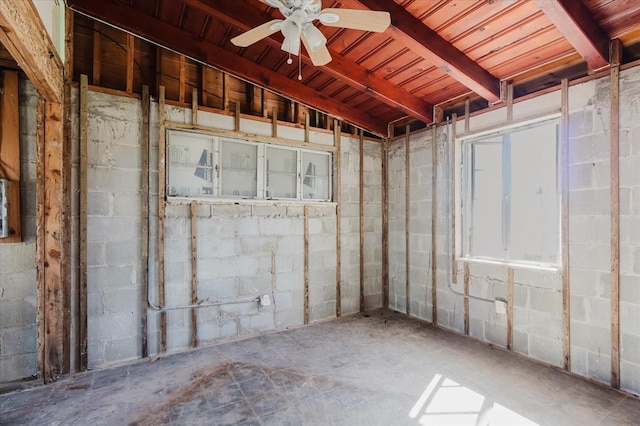 basement with concrete block wall and a ceiling fan