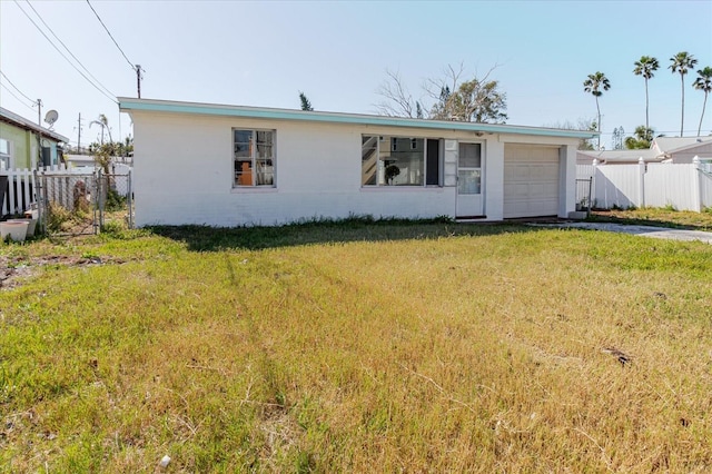 ranch-style house with a front lawn, an attached garage, and fence