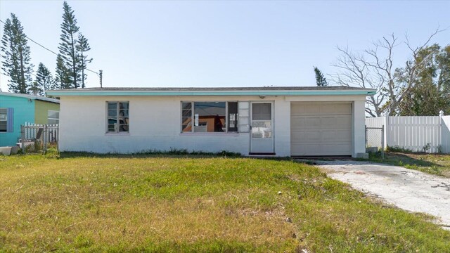 single story home with a front lawn, driveway, fence, an attached garage, and concrete block siding