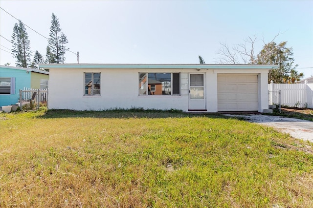 ranch-style house with fence, driveway, an attached garage, stucco siding, and a front lawn