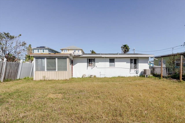 back of property featuring a yard, cooling unit, and fence