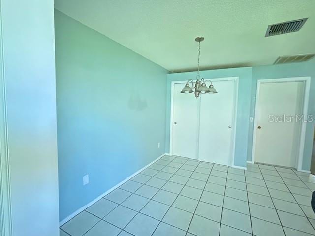 unfurnished dining area featuring light tile patterned floors, visible vents, baseboards, and a chandelier