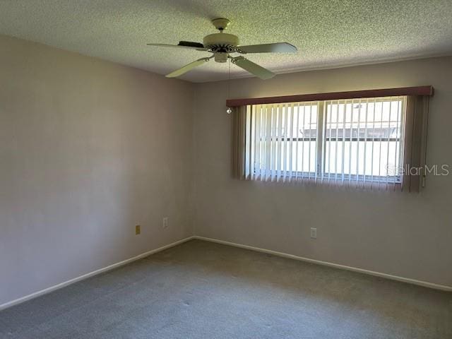 empty room with baseboards, a textured ceiling, carpet, and a ceiling fan