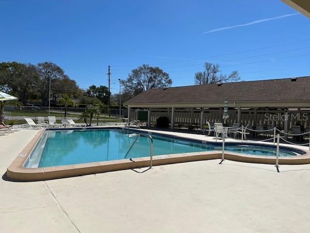 community pool with a patio and fence