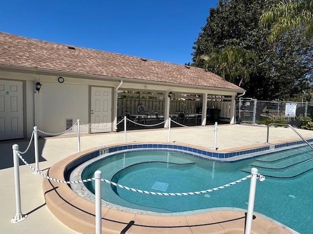 community pool with a patio area and fence