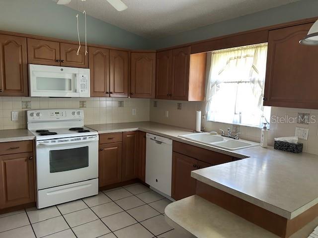 kitchen featuring white appliances, lofted ceiling, a peninsula, and light countertops