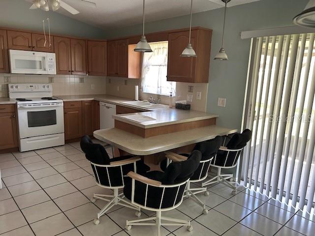 kitchen featuring white appliances, light tile patterned floors, a sink, light countertops, and tasteful backsplash