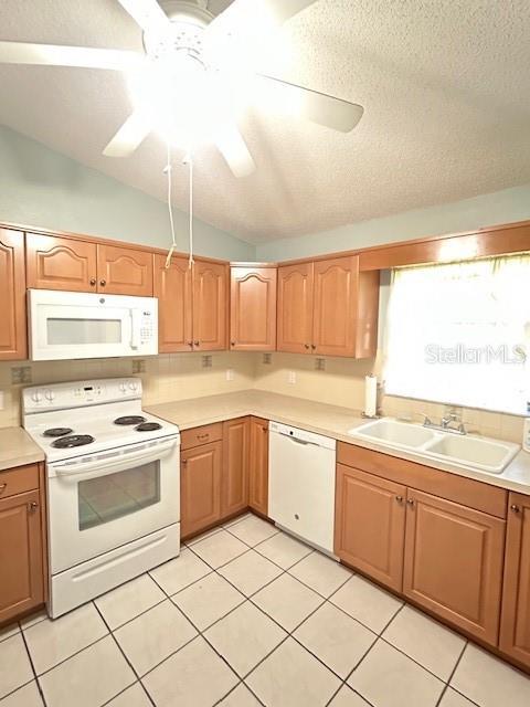 kitchen featuring white appliances, a ceiling fan, a sink, vaulted ceiling, and light countertops