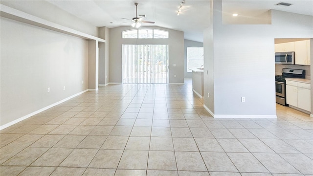 empty room featuring visible vents, light tile patterned floors, baseboards, ceiling fan, and vaulted ceiling