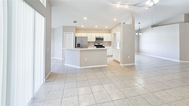 kitchen featuring a center island with sink, open floor plan, stainless steel appliances, light tile patterned floors, and vaulted ceiling