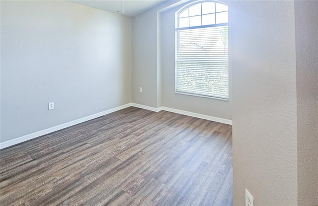 spare room with dark wood-style floors and baseboards