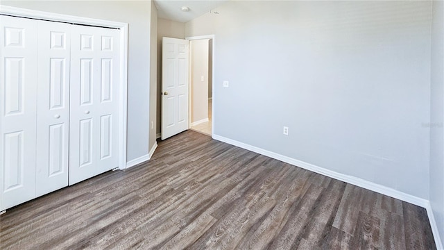 unfurnished bedroom featuring a closet, baseboards, and wood finished floors