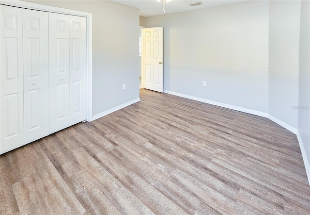 unfurnished bedroom featuring a closet, baseboards, and wood finished floors