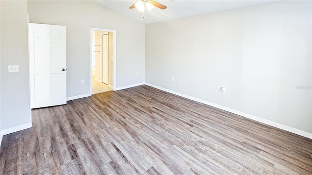 spare room featuring lofted ceiling, wood finished floors, baseboards, and ceiling fan