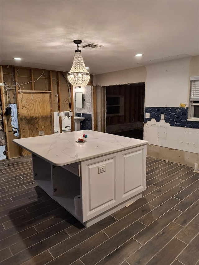 kitchen with white cabinets, wood finish floors, a center island, and visible vents