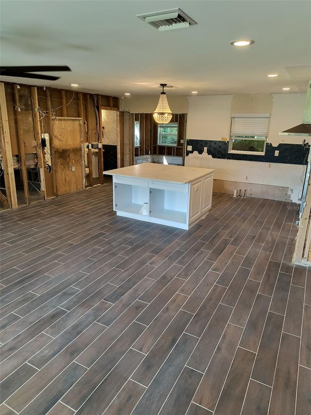 kitchen with light countertops, pendant lighting, white cabinetry, wood tiled floor, and visible vents