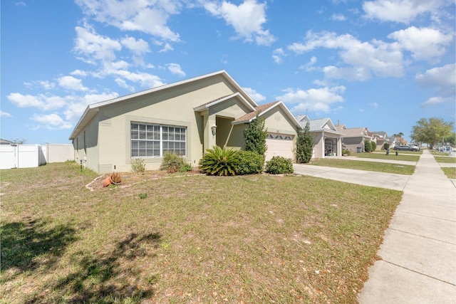 view of front of home with stucco siding, driveway, fence, a front yard, and an attached garage