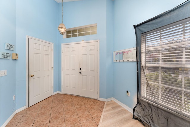 entrance foyer with light tile patterned flooring, baseboards, and a towering ceiling