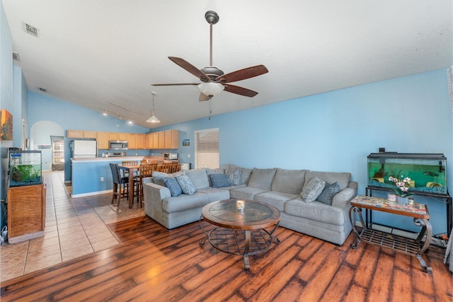 living room with visible vents, ceiling fan, vaulted ceiling, wood finished floors, and arched walkways