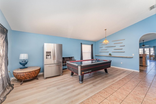 recreation room with light wood finished floors, visible vents, ceiling fan, lofted ceiling, and arched walkways