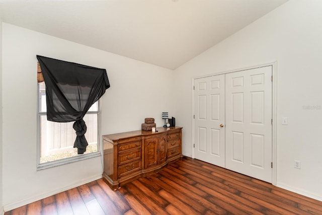 bedroom with vaulted ceiling, dark wood-style floors, baseboards, and a closet