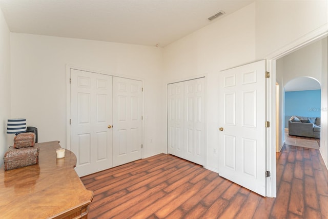 home office with visible vents, arched walkways, and dark wood-style flooring