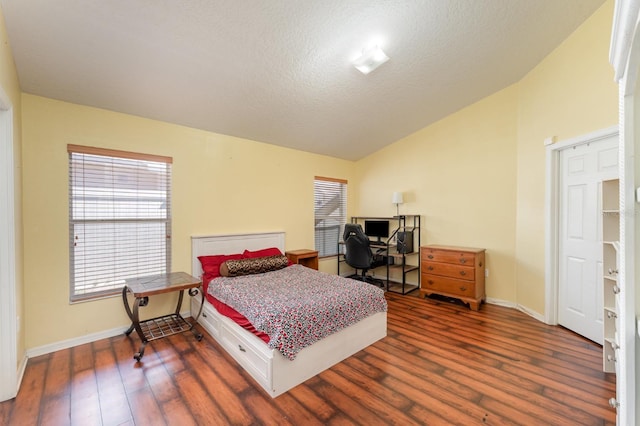 bedroom with a textured ceiling, wood finished floors, baseboards, and vaulted ceiling