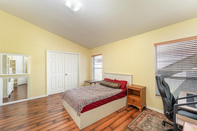 bedroom with lofted ceiling, wood finished floors, baseboards, and a textured ceiling