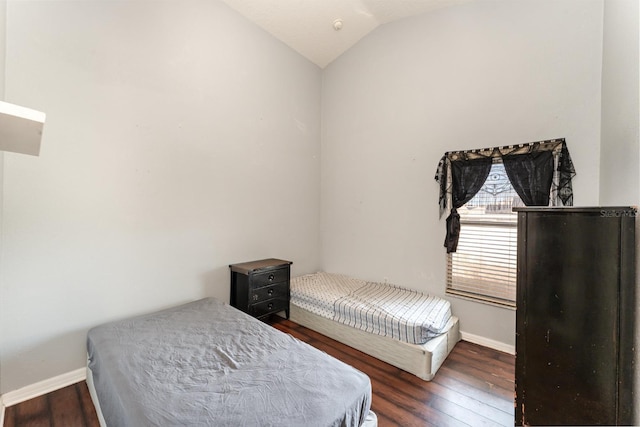 bedroom with baseboards, lofted ceiling, and wood finished floors