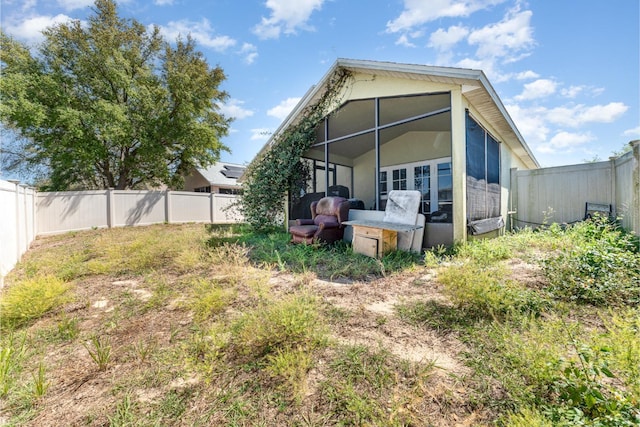 back of property with a fenced backyard and a sunroom