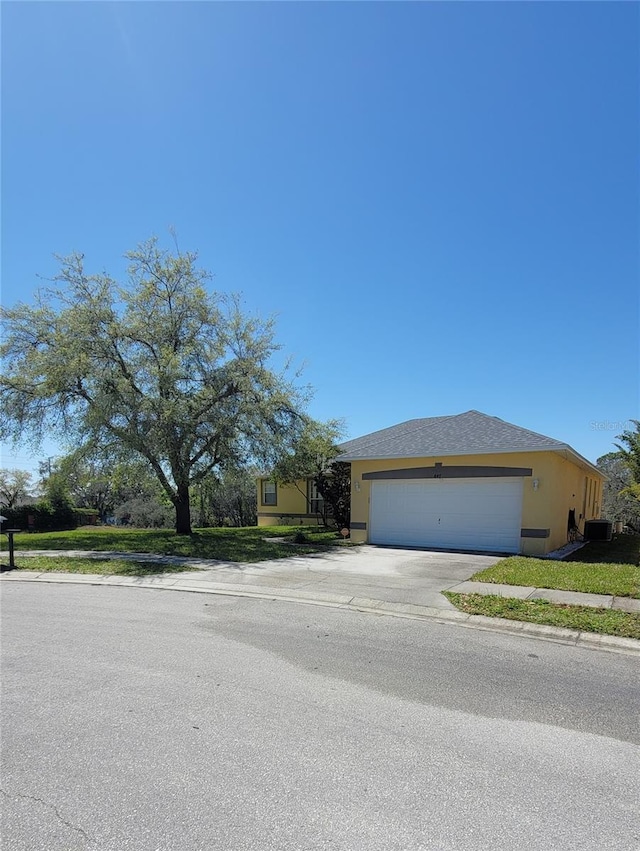 view of front of home with central air condition unit, stucco siding, an attached garage, and concrete driveway