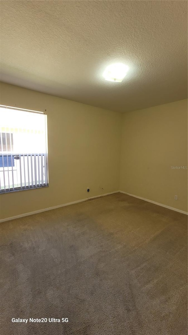 carpeted spare room with baseboards and a textured ceiling