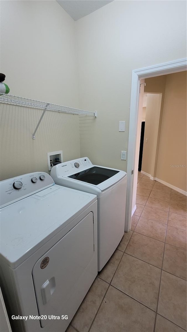 laundry room with light tile patterned floors, baseboards, separate washer and dryer, and laundry area