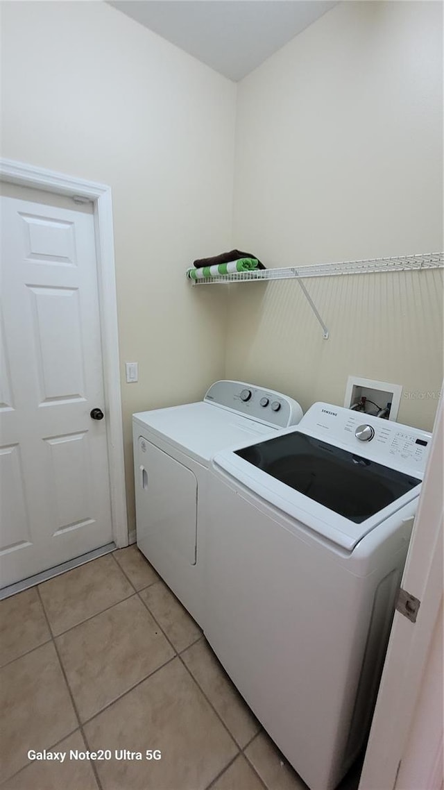 clothes washing area with light tile patterned floors, laundry area, and washing machine and dryer